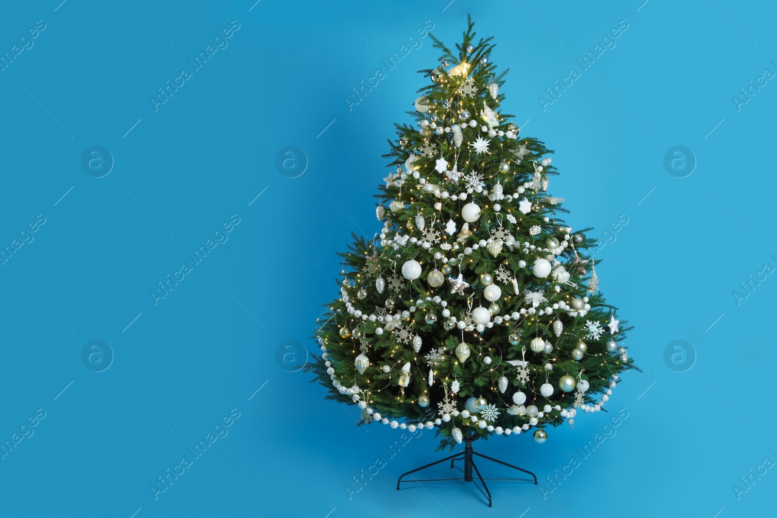 Photo of Beautifully decorated Christmas tree on light blue background