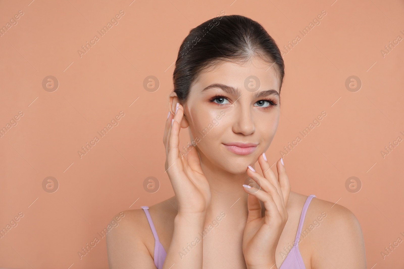 Photo of Portrait of pretty girl on pale coral background, space for text. Beautiful face with perfect smooth skin