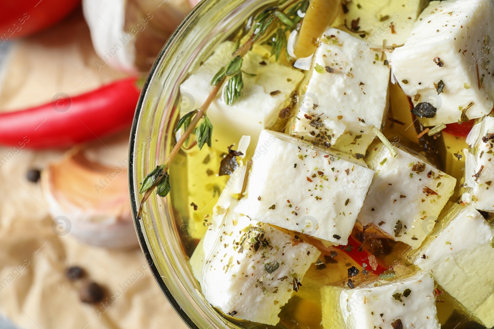 Photo of Top view of pickled feta cheese in jar on table, closeup