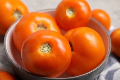 Many ripe yellow tomatoes in bowl on table, closeup