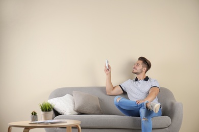 Young man with air conditioner remote at home