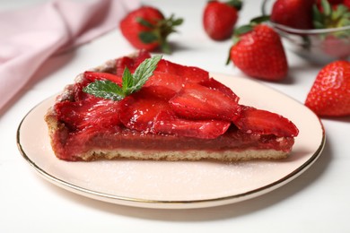 Photo of Piece of delicious strawberry tart with mint on white wooden table, closeup