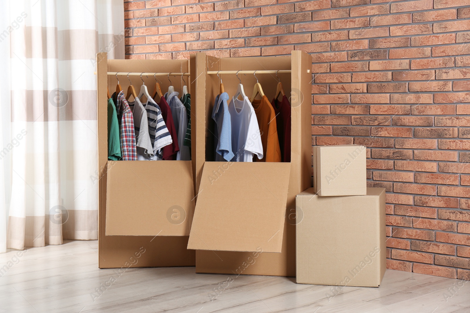 Photo of Wardrobe boxes with clothes against brick wall indoors