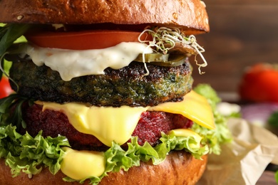 Photo of Vegan burger with beet and falafel patties on blurred background, closeup