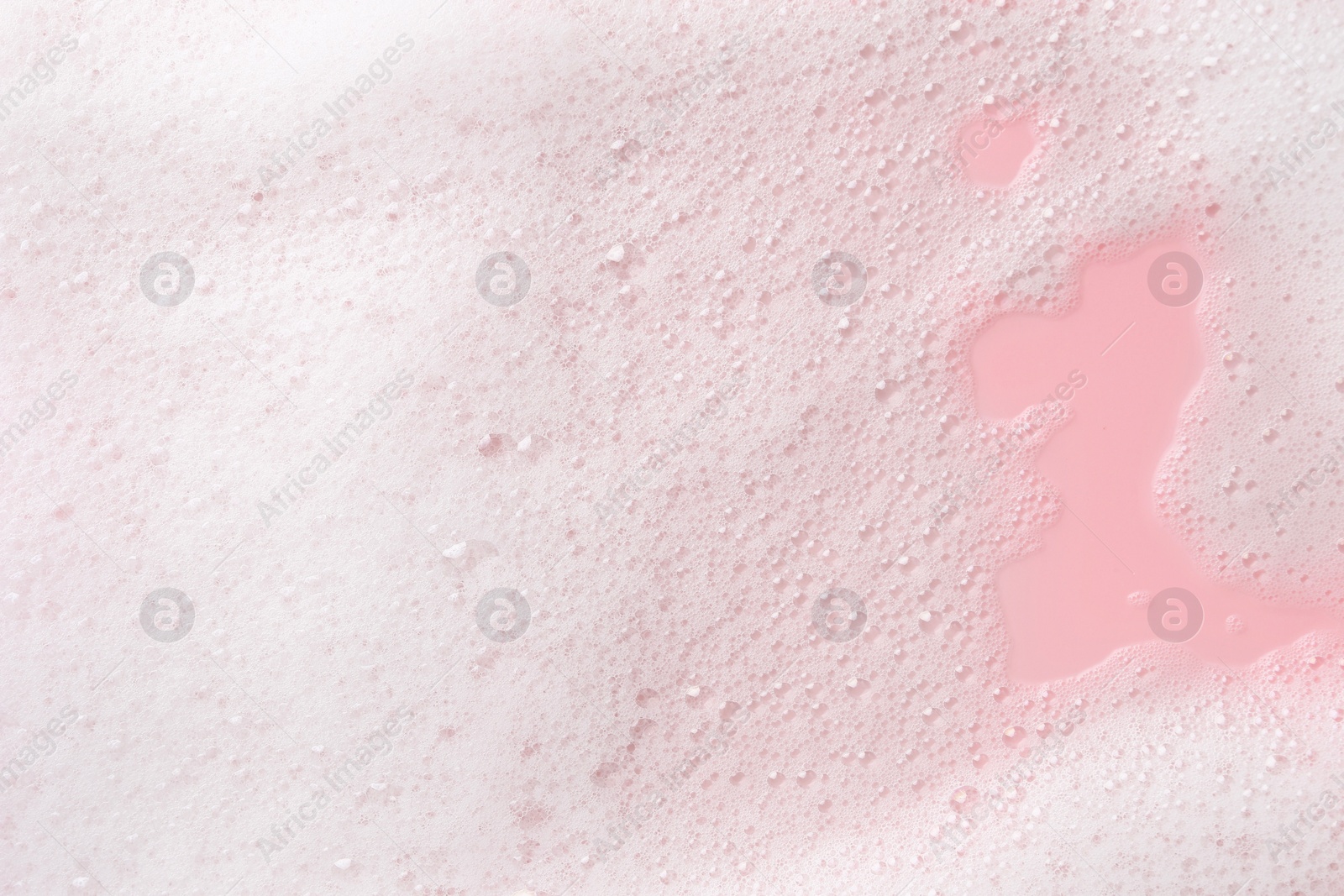 Photo of White fluffy foam on pink background, top view