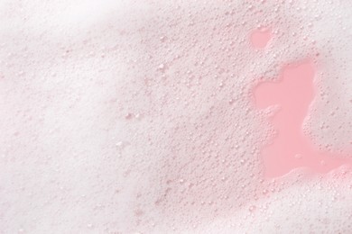 White fluffy foam on pink background, top view