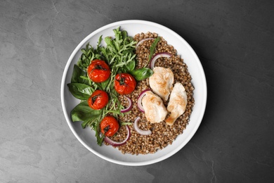 Tasty buckwheat porridge with meat and vegetables on grey table, top view