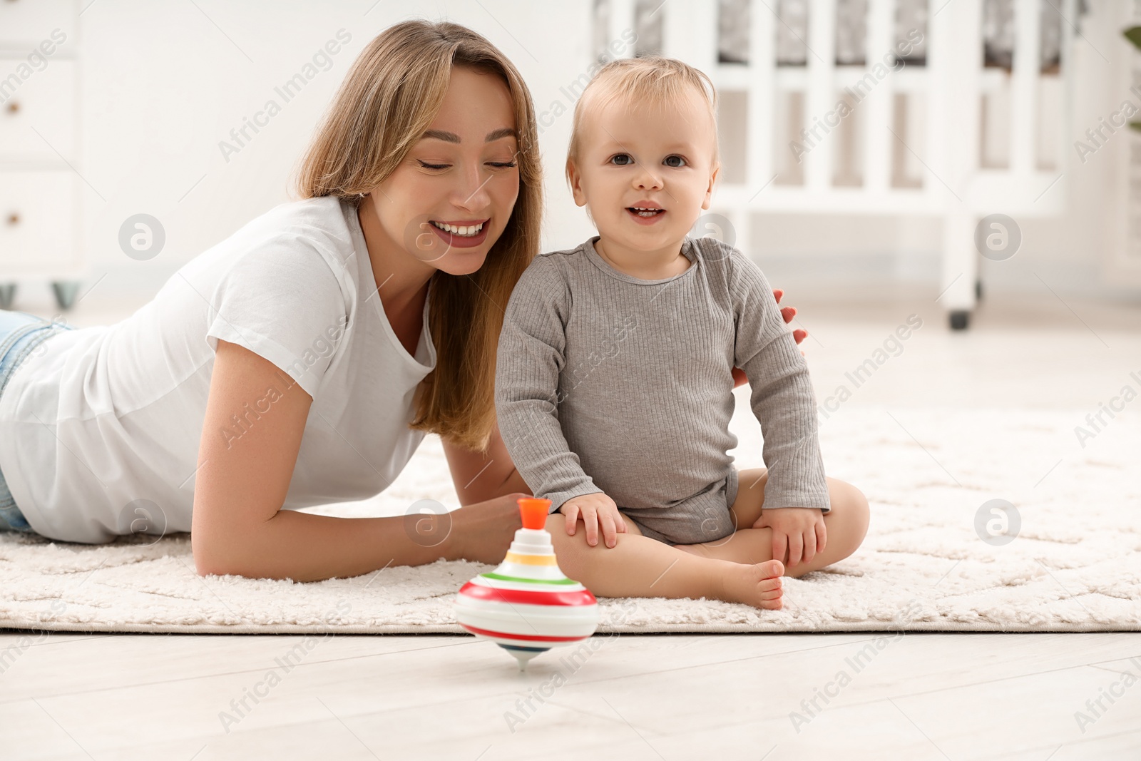 Photo of Children toys. Happy mother with her little son and spinning top on rug at home