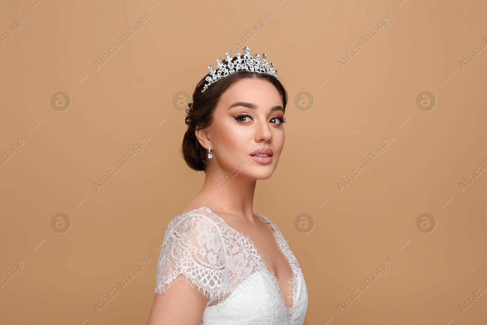 Photo of Beautiful young woman wearing luxurious tiara on beige background