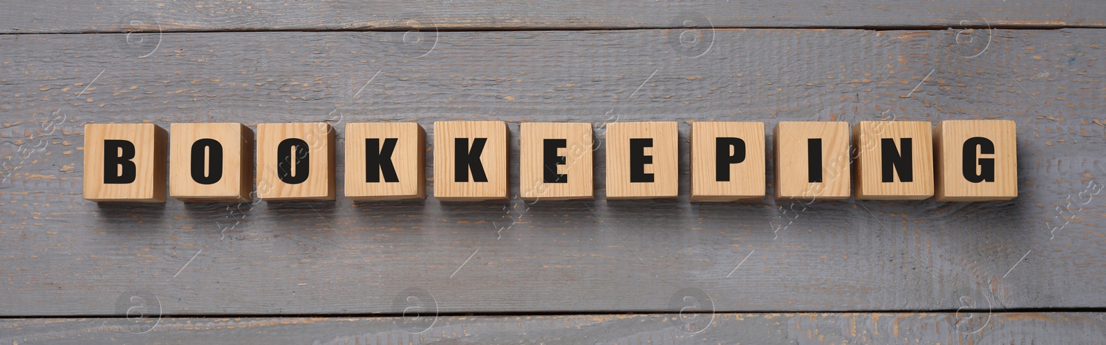 Photo of Word Bookkeeping made of cubes on grey wooden table, top view