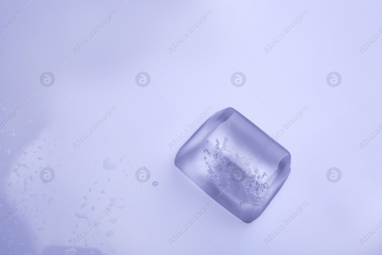 Photo of Ice cube on color background. Space for text