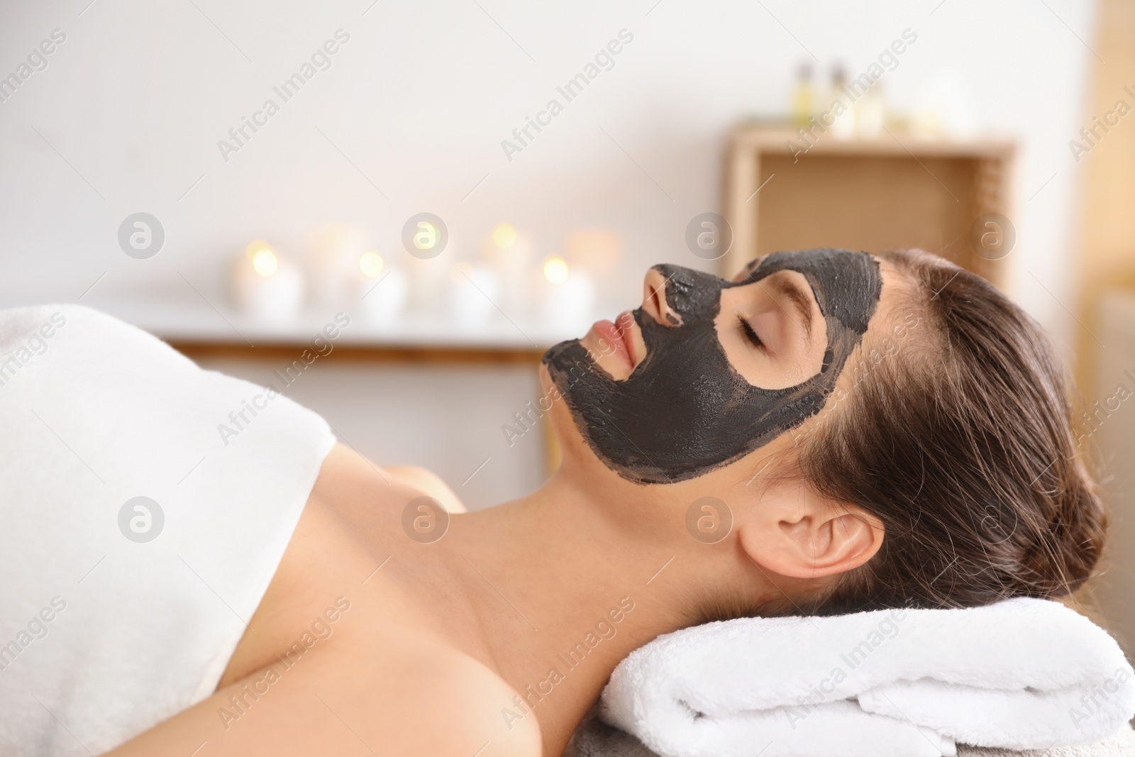 Photo of Beautiful woman with black mask on face relaxing in spa salon