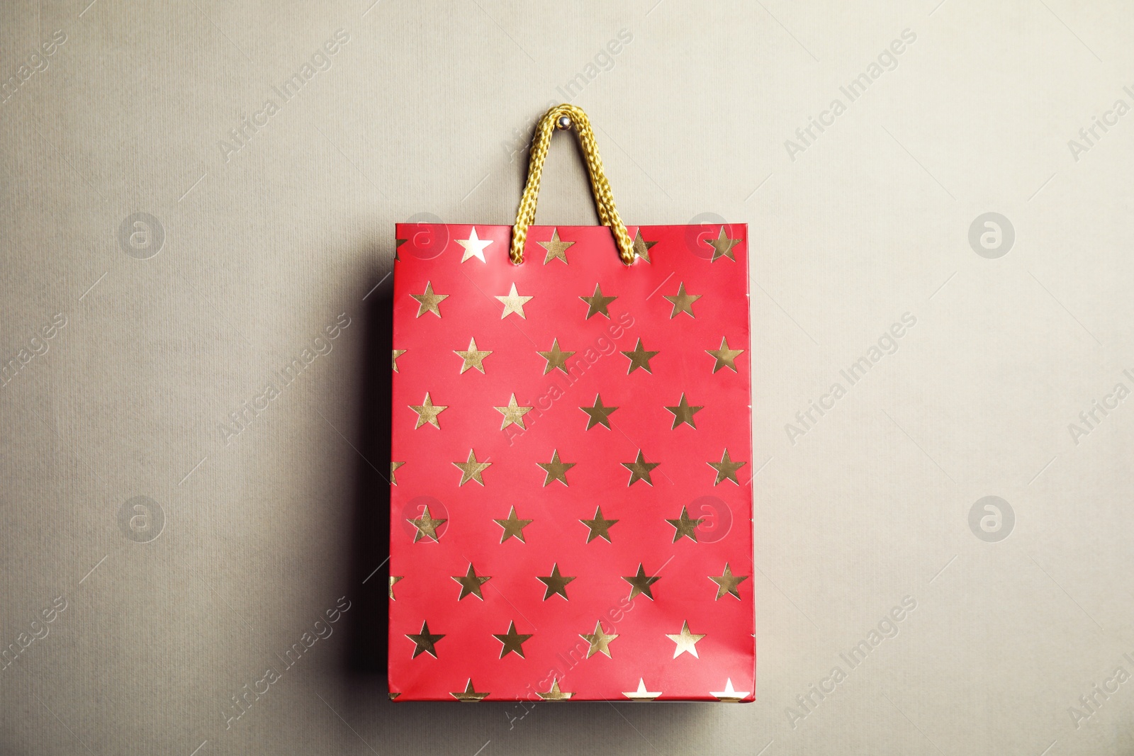 Photo of Red shopping paper bag with star pattern on grey background