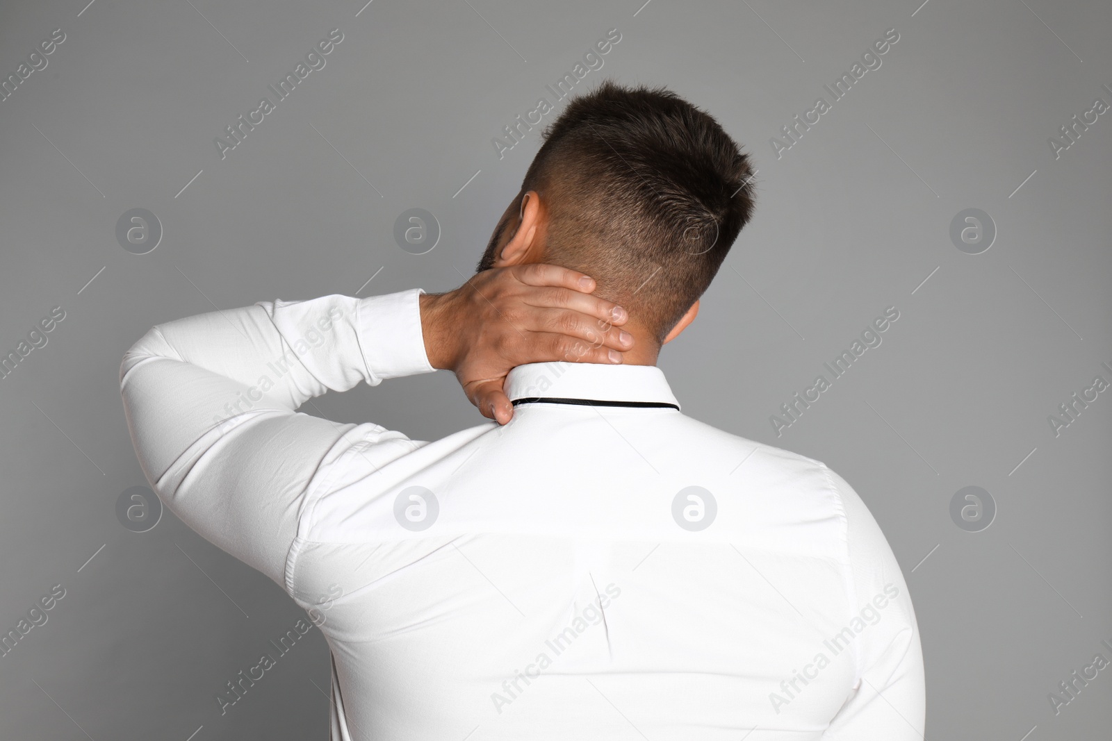 Photo of Businessman suffering from neck pain on light grey background