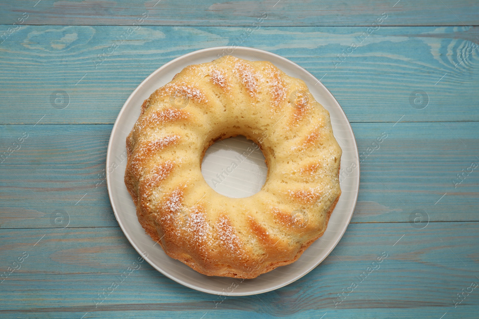 Photo of Delicious freshly baked sponge cake on light blue wooden table, top view