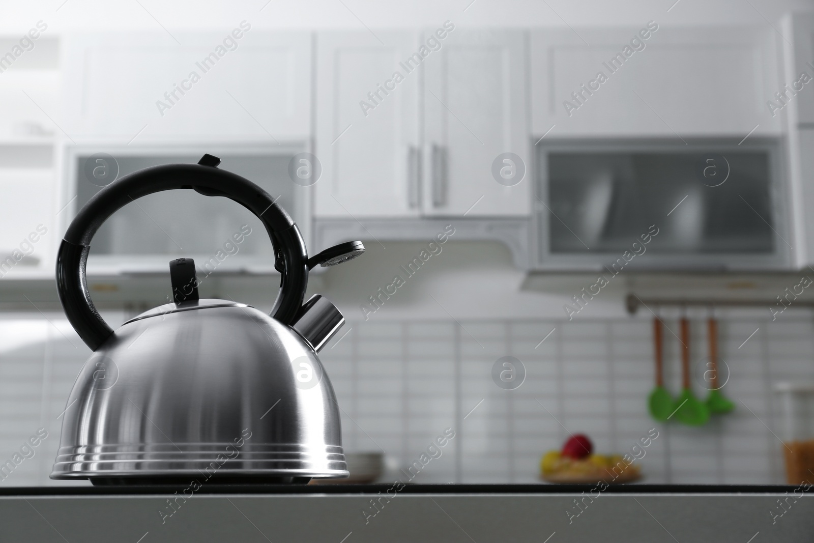 Photo of Modern kettle with whistle on stove in kitchen, space for text