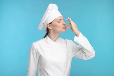 Photo of Woman chef in uniform showing perfect sign on light blue background