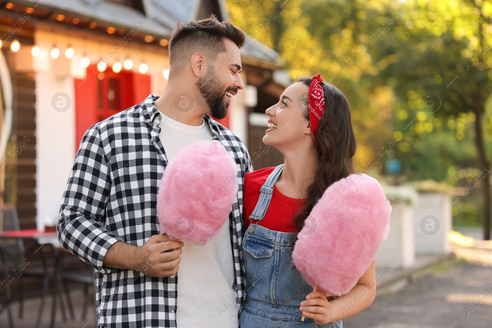 Photo of Happy couple with cotton candies spending time together outdoors