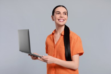 Photo of Happy woman with laptop on light gray background