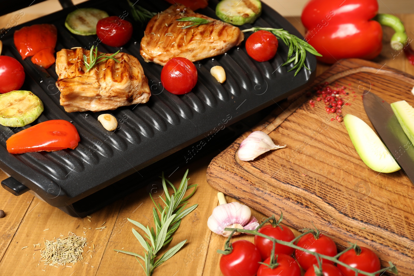 Photo of Electric grill with different products on wooden table