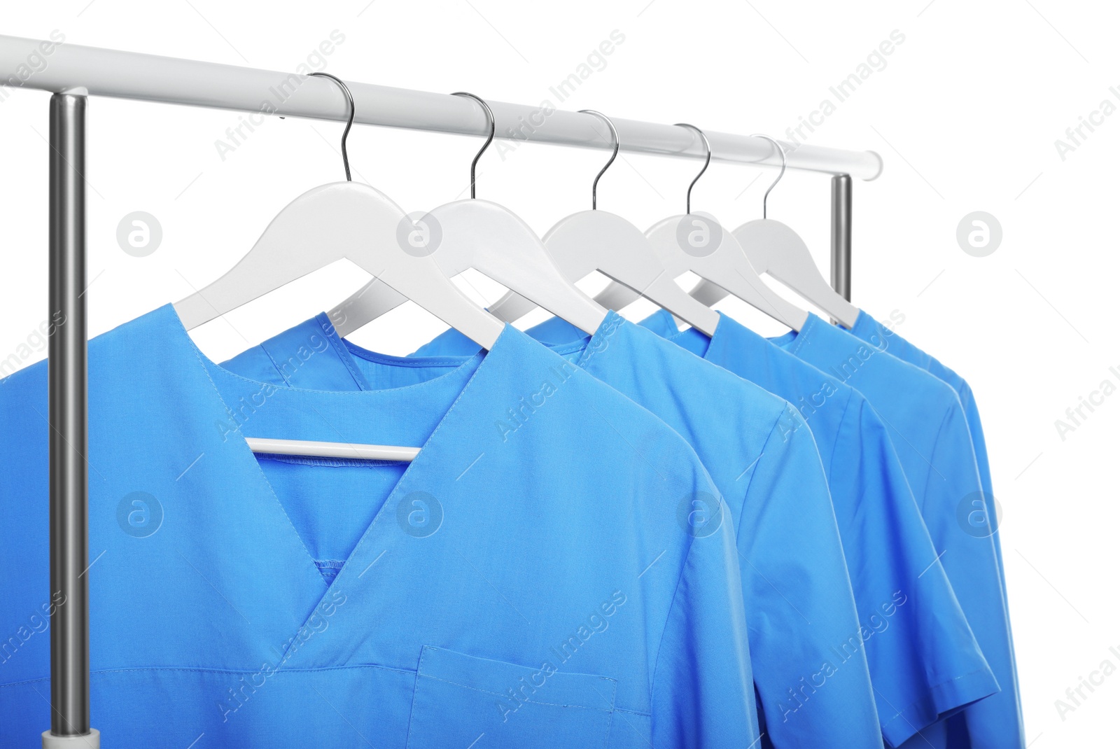 Photo of Light blue medical uniforms on rack against white background