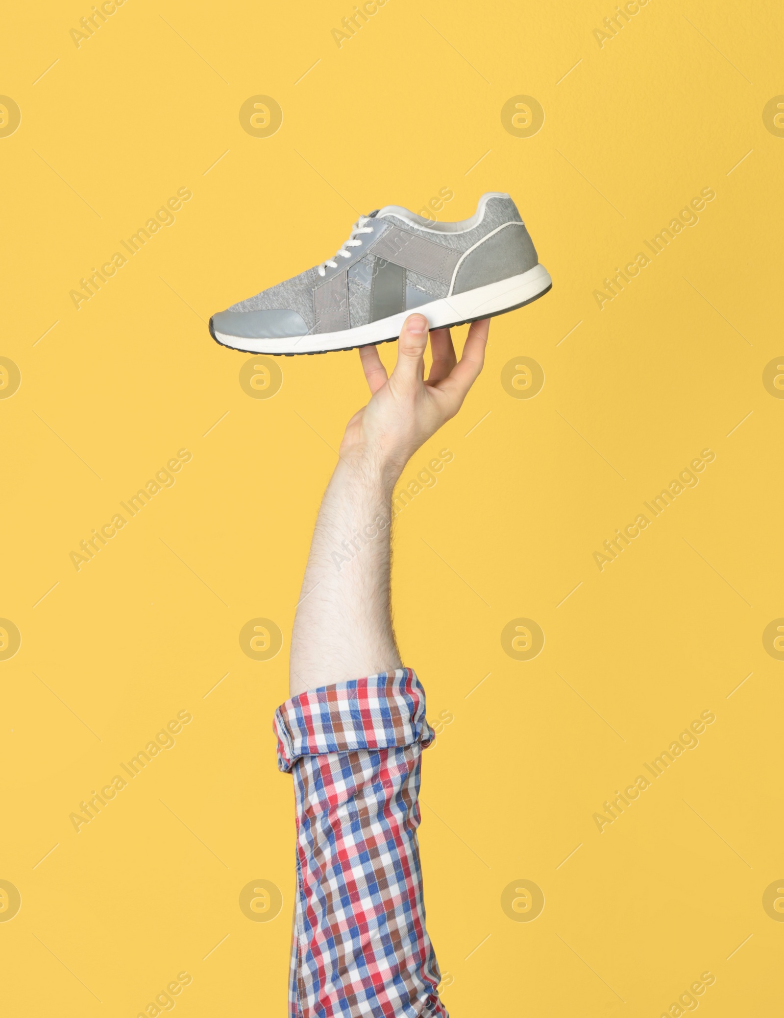 Photo of Man holding stylish shoe on yellow background, closeup