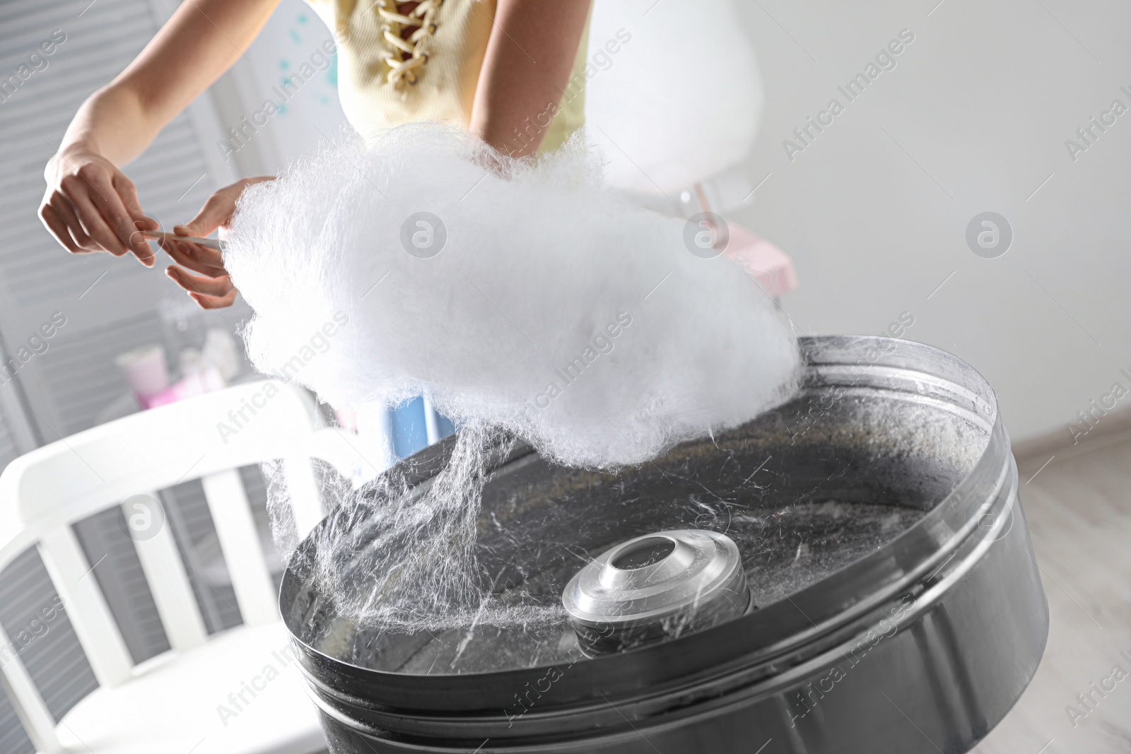 Photo of Woman making cotton candy using modern machine indoors, closeup