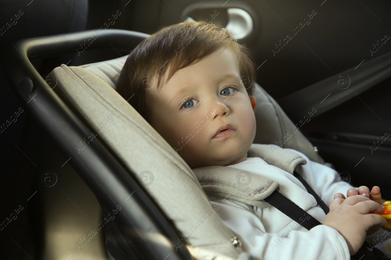 Photo of Cute little boy sitting in child safety seat inside car