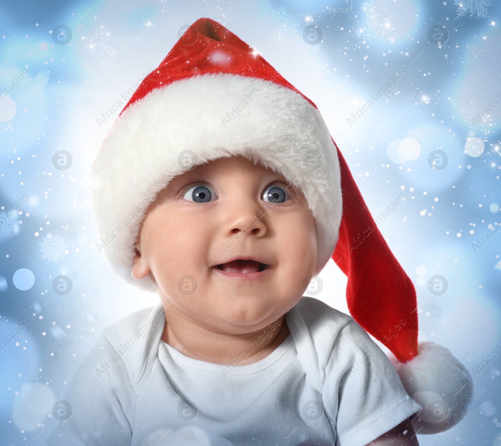 Image of Cute baby in Santa hat against blurred lights. Christmas celebration
