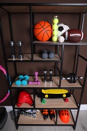 Photo of Shelving unit with different sports equipment near brown wall indoors