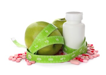 Photo of Weight loss pills, apples and measuring tape on white background