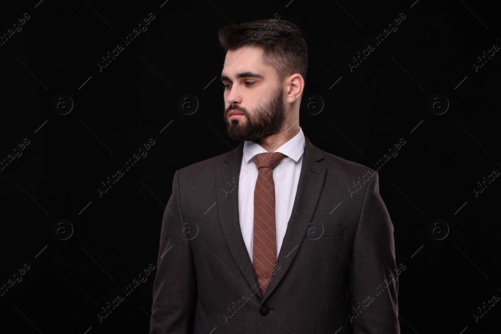 Photo of Handsome businessman in suit and necktie on black background