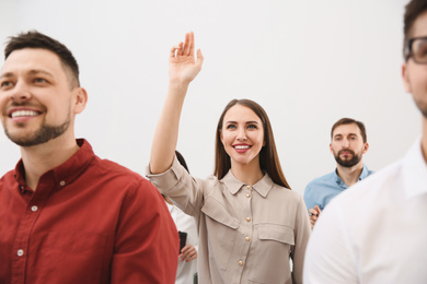 Photo of Young woman raising hand to ask question at business training on white background