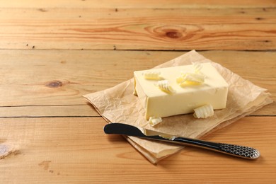 Tasty butter and knife on wooden table. Space for text