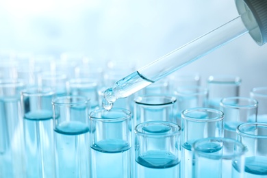 Photo of Dropping sample into test tube with light blue liquid, closeup