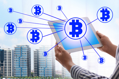 Image of Fintech concept. Scheme with bitcoin symbols and man using tablet on cityscape background