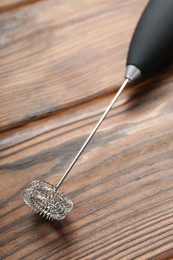 Black milk frother wand on wooden table, above view