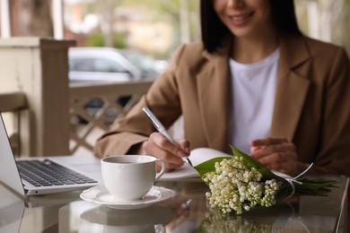 Photo of Woman with cup of coffee working at outdoor cafe in morning, closeup