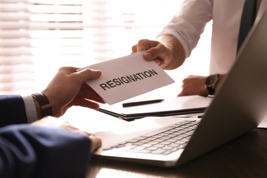 Employee giving resignation letter to boss in office, closeup