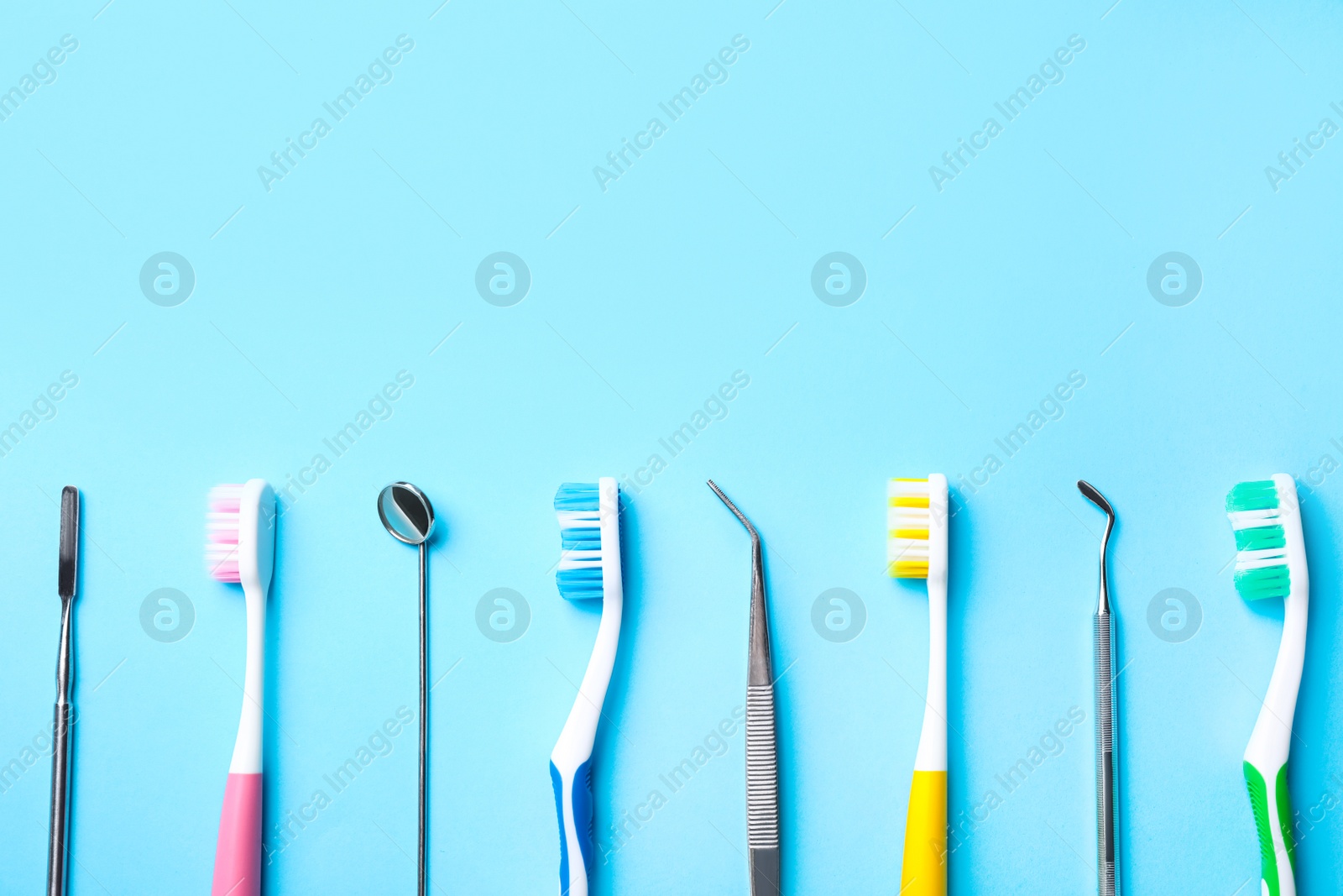 Photo of Different toothbrushes and dental tools on light blue background, flat lay. Space for text