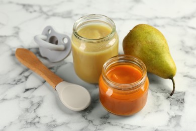 Photo of Tasty baby food in jars, pear and spoon on white marble table