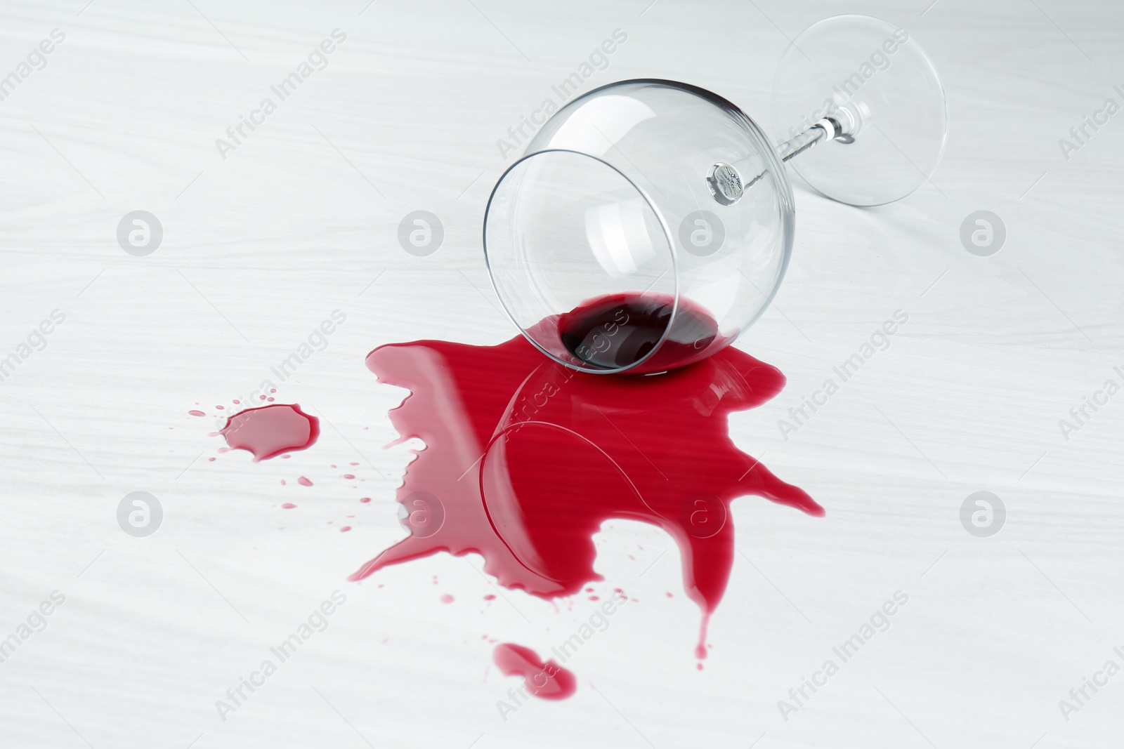 Photo of Overturned glass and spilled wine on white wooden table