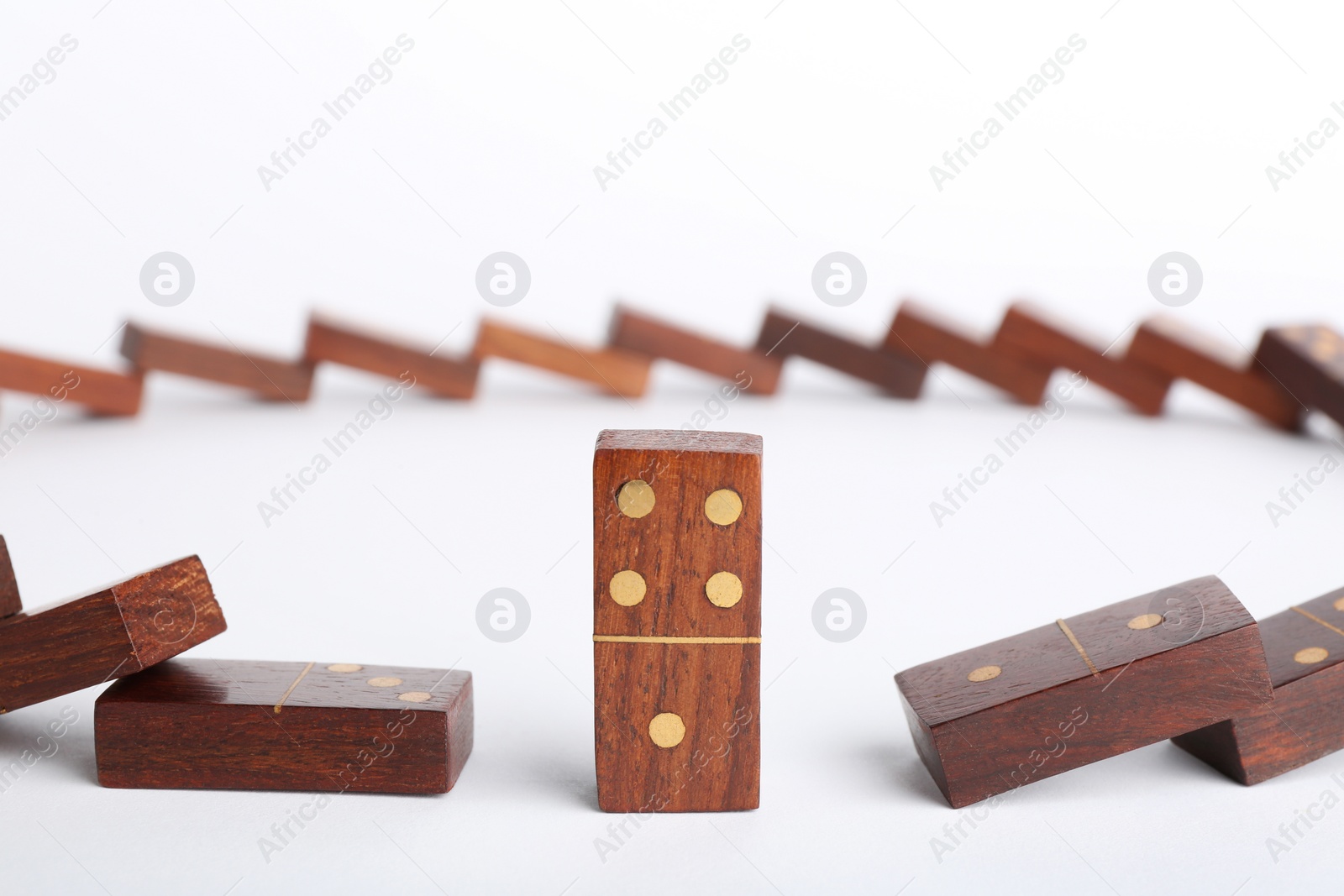 Photo of Standing domino piece among fallen ones on white background