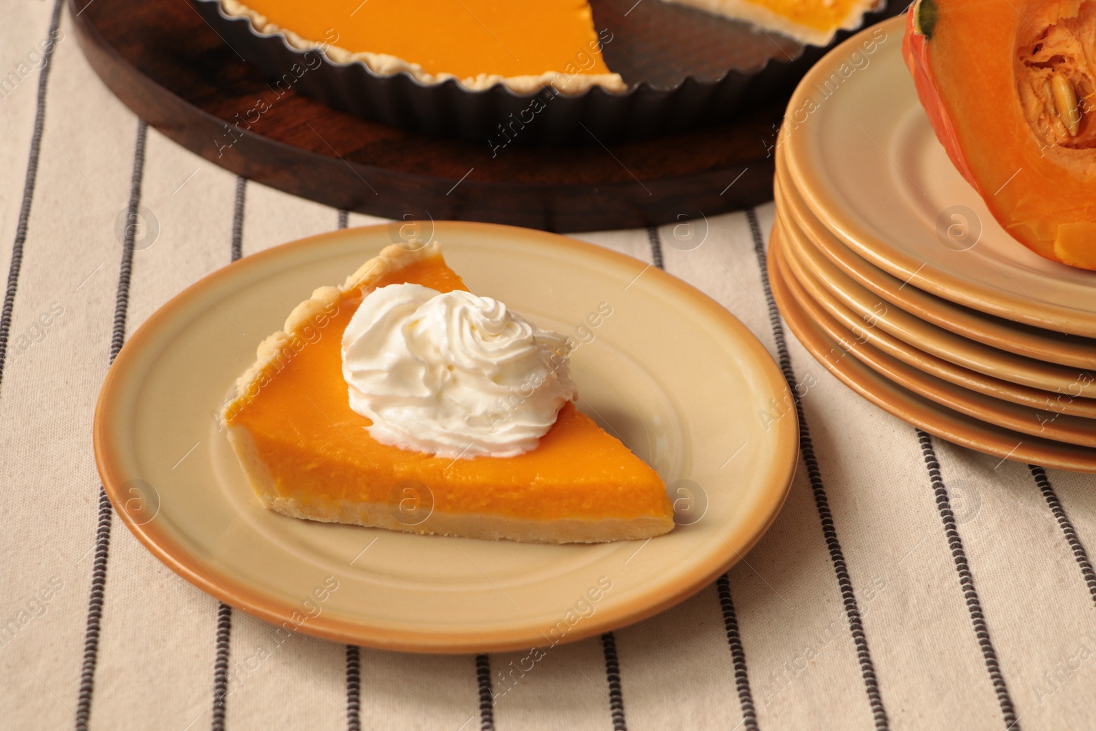 Photo of Piece of fresh homemade pumpkin pie with whipped cream on table