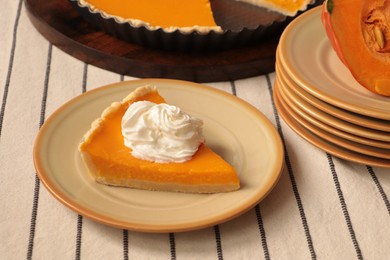 Piece of fresh homemade pumpkin pie with whipped cream on table