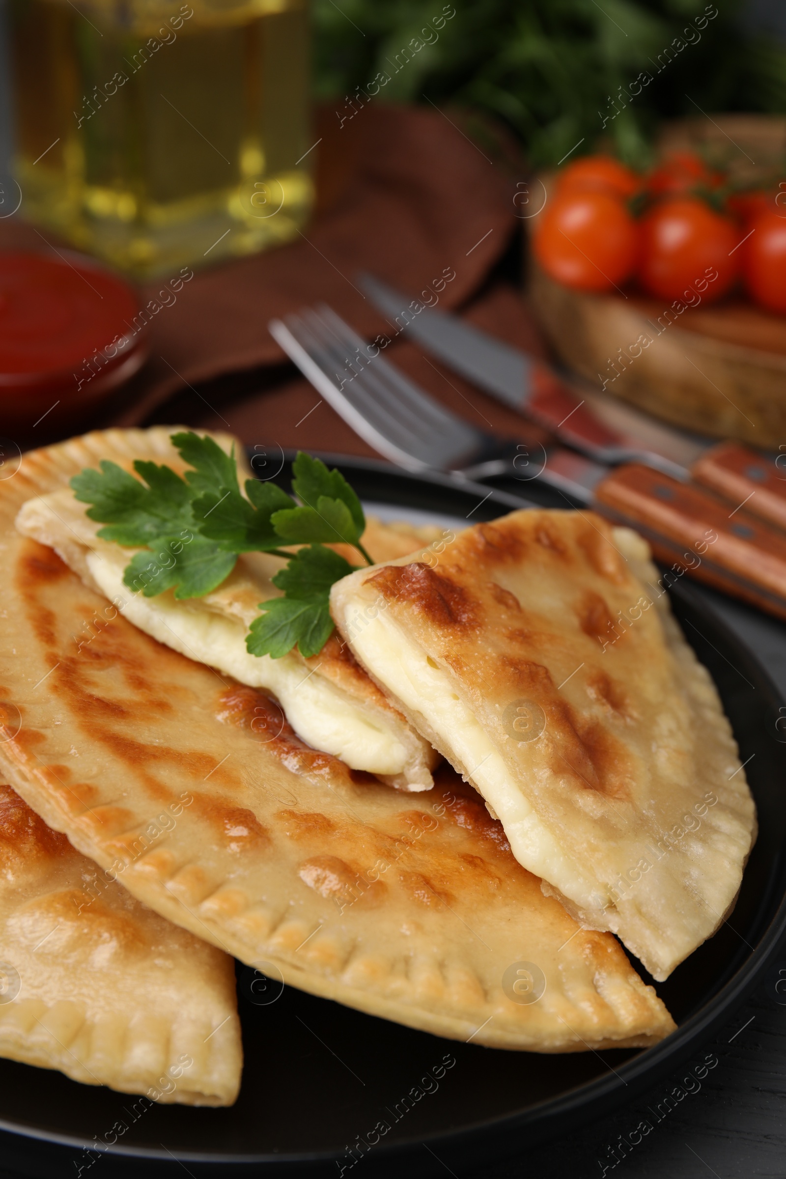 Photo of Delicious fried chebureki with cheese and parsley on grey table, closeup