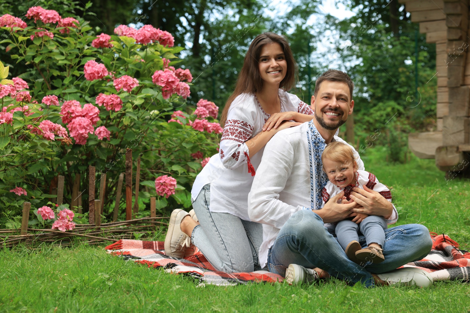 Photo of Happy family in Ukrainian national clothes on green grass outdoors