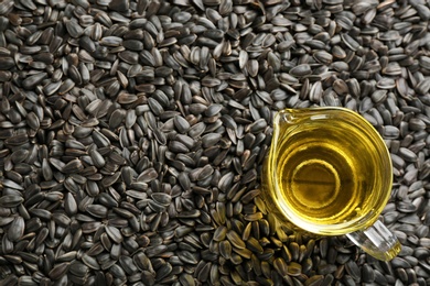 Photo of Sunflower seeds and jug with oil as background