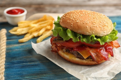 Tasty burger with bacon on wooden board. Space for text