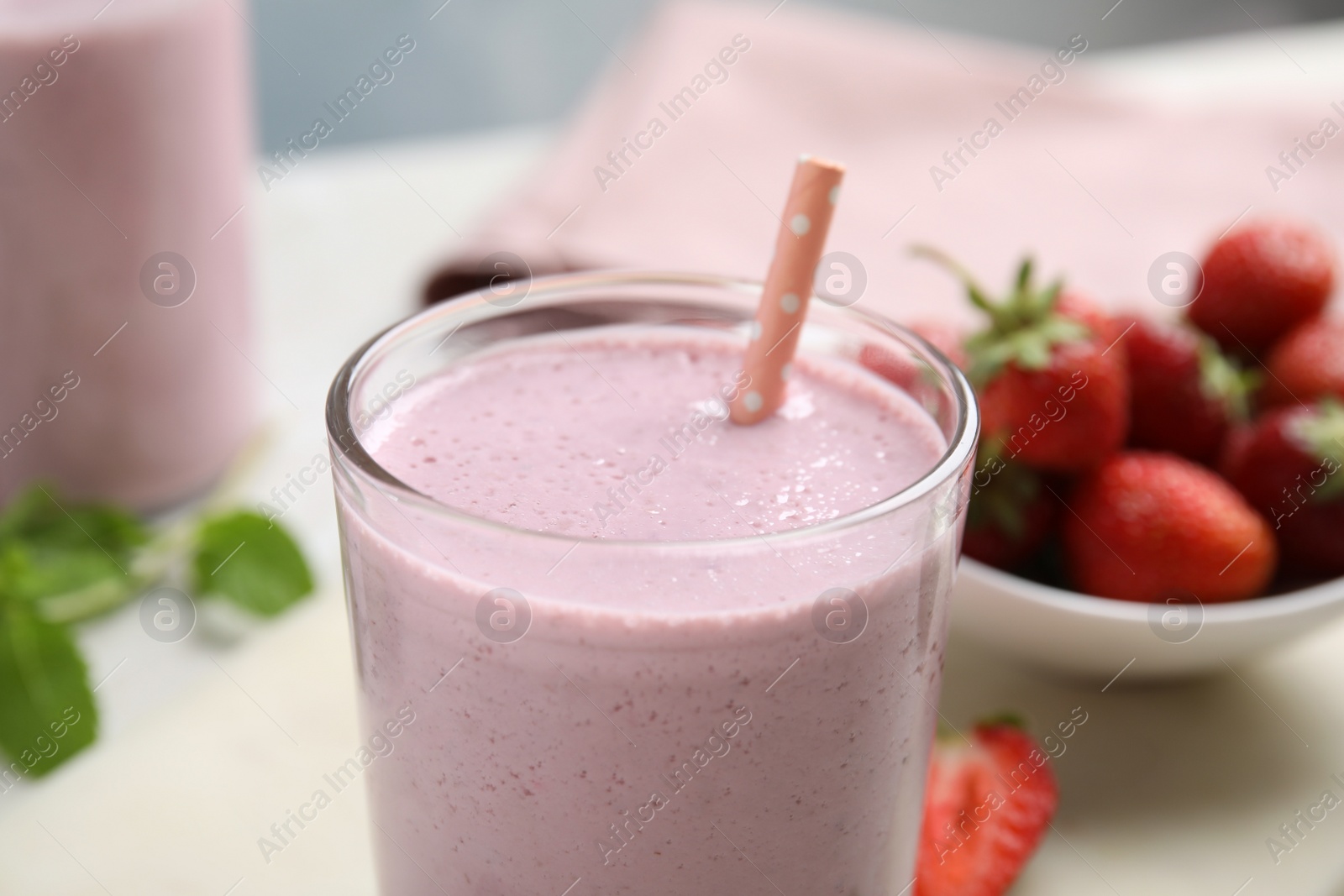 Photo of Tasty milk shake with straw on light table, closeup